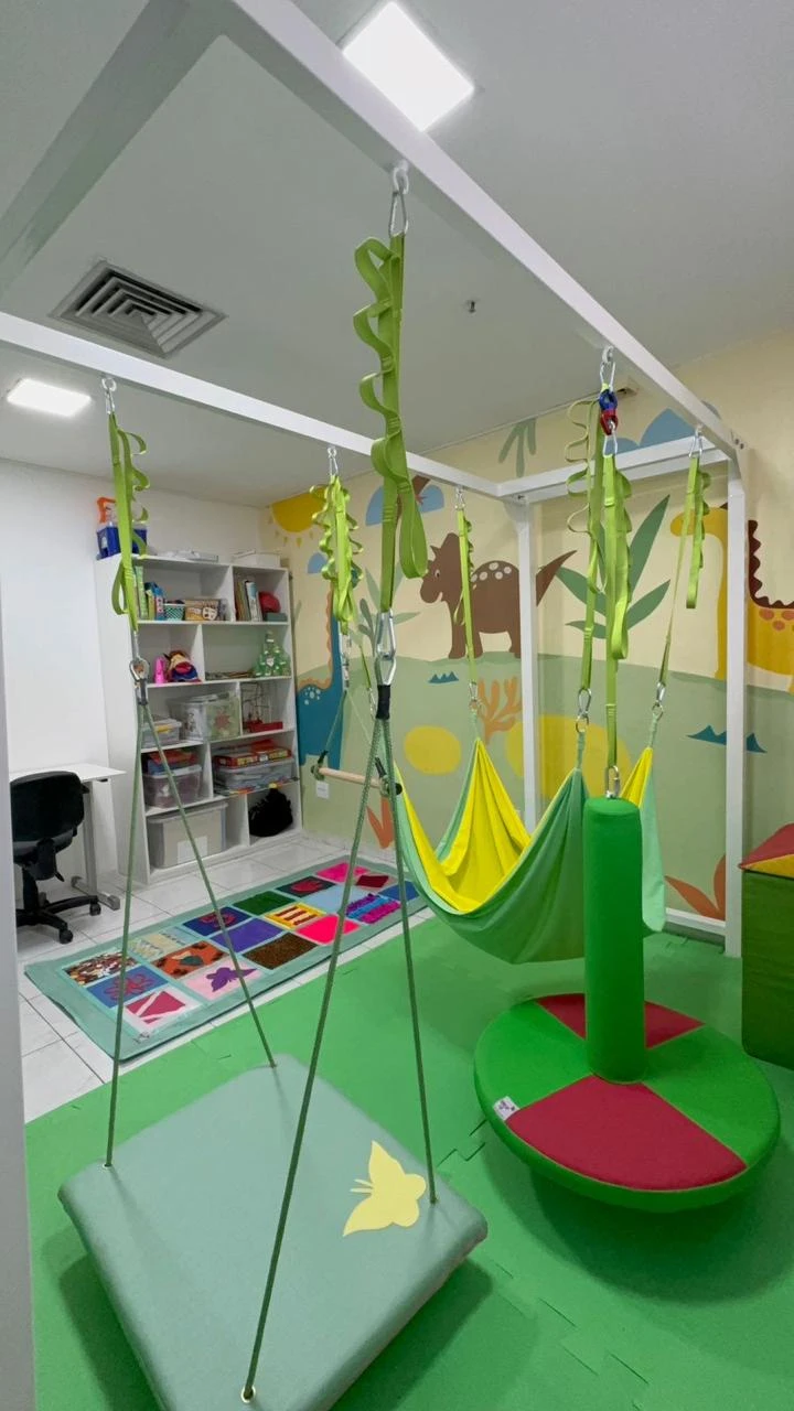 Sala de integração sensorial, com balanços e estante de jogos